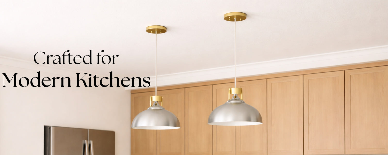 Two modern dome pendant lights with gold accents and silver shades hanging above a bright kitchen with wood cabinets.